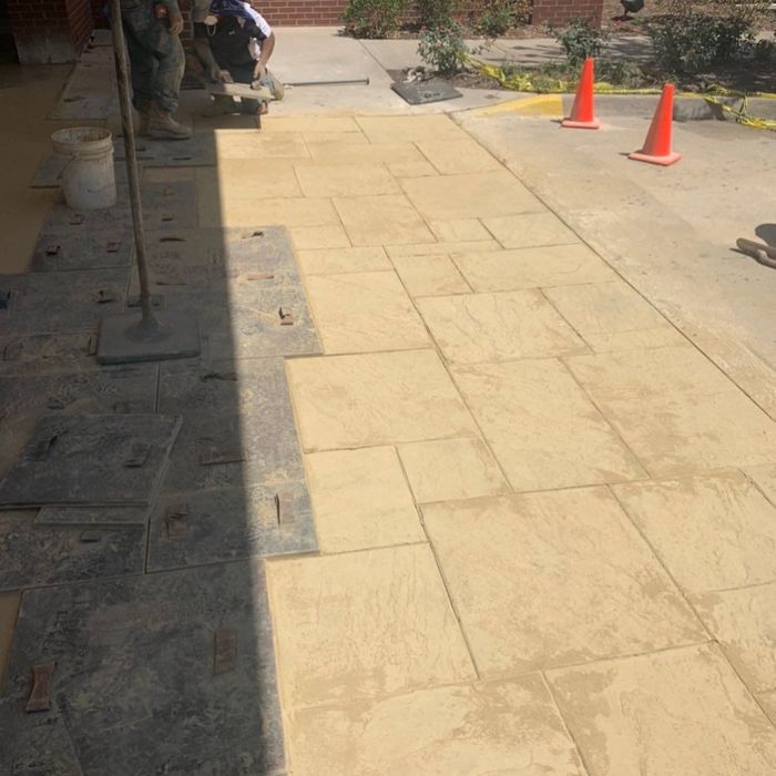Sunny sidewalk with orange cones and a person near a building entrance