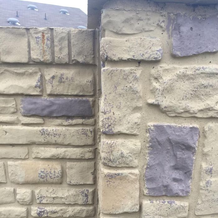 Close-up of a beige stone wall with stacked blocks and a few gray accent stones