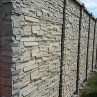 Stone wall with stacked beige and gray blocks along a narrow outdoor path