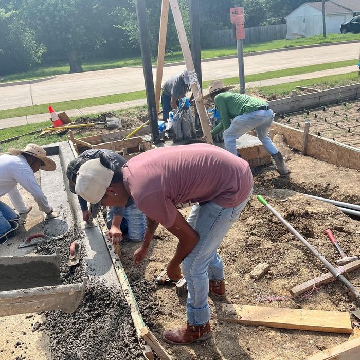 Construction crew pouring concrete and leveling a sidewalk curb at an outdoor worksite