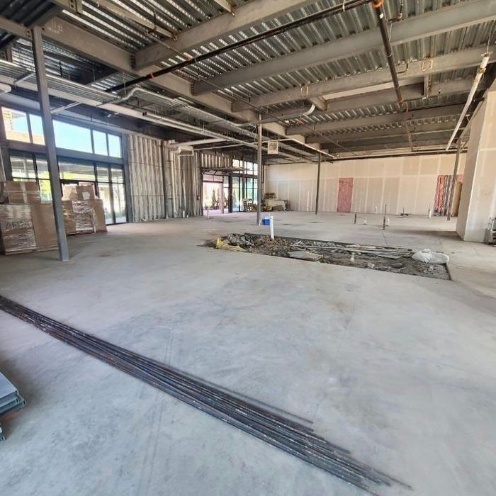 Empty industrial warehouse interior with exposed beams, concrete floor, and large open space