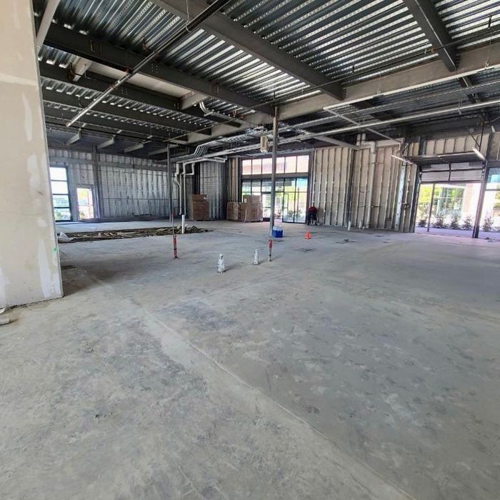Empty unfinished industrial interior with exposed steel beams, concrete floor, and windowed walls
