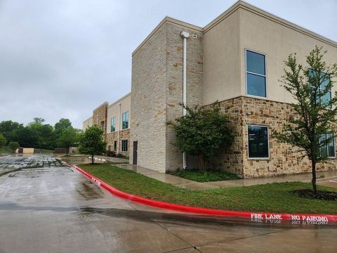 Rainy apartment building exterior with stone facade, wet parking lot, and red curb