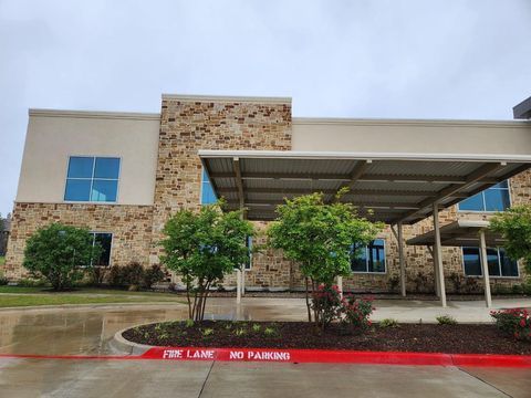 Modern building entrance with stone facade, covered drop-off, and landscaped curbside area