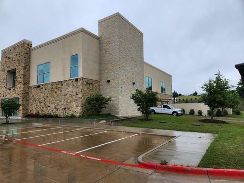 Brick building with wet parking lot, red curb markings, and a white car parked nearby