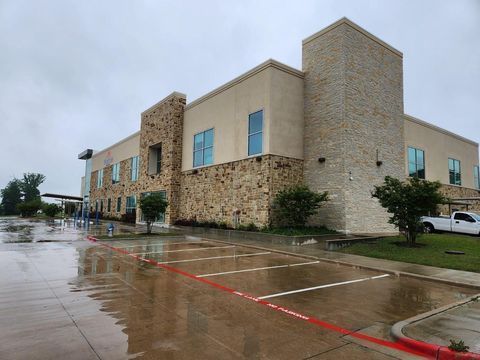 Rain-soaked parking lot beside a beige stone office building with blue windows and a parked white SUV