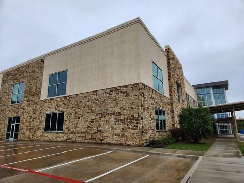 Stone office building with blue windows and empty parking spaces on an overcast day
