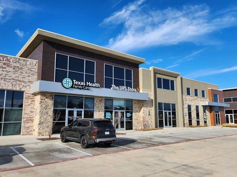 Modern medical office building with stone facade, glass windows, and a parked black SUV in front