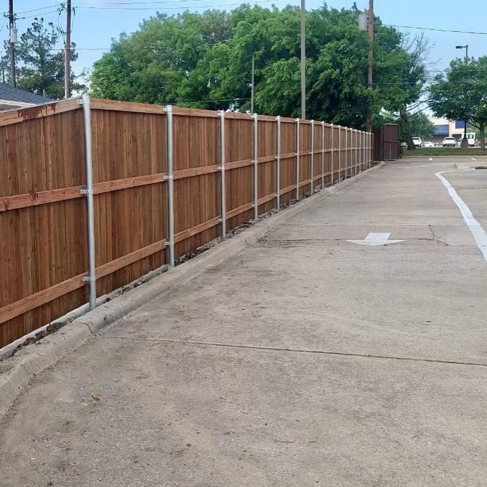 Long wooden fence beside a concrete alley or parking lane on a cloudy day