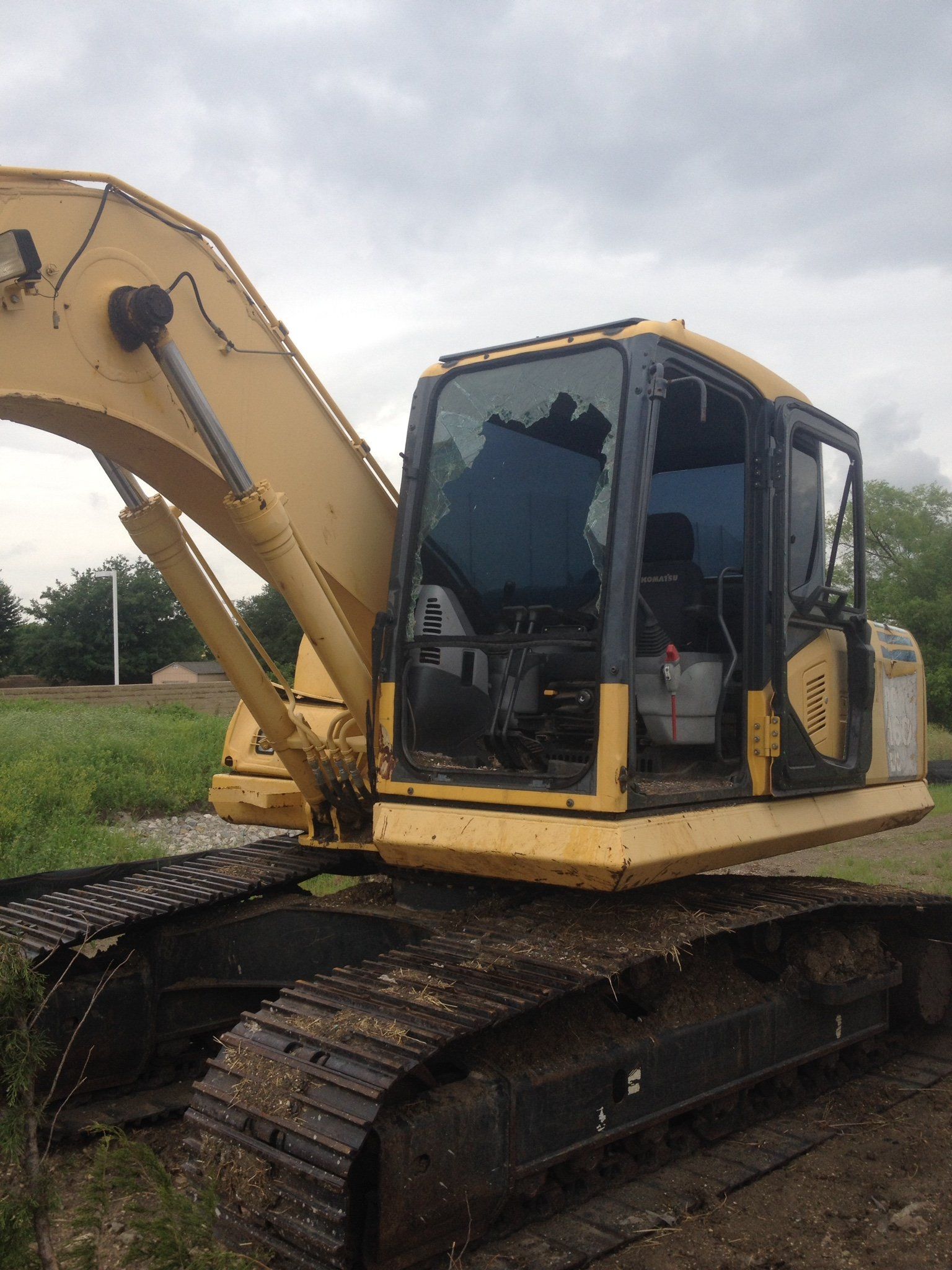 Yellow tracked excavator on a muddy construction site under cloudy sky