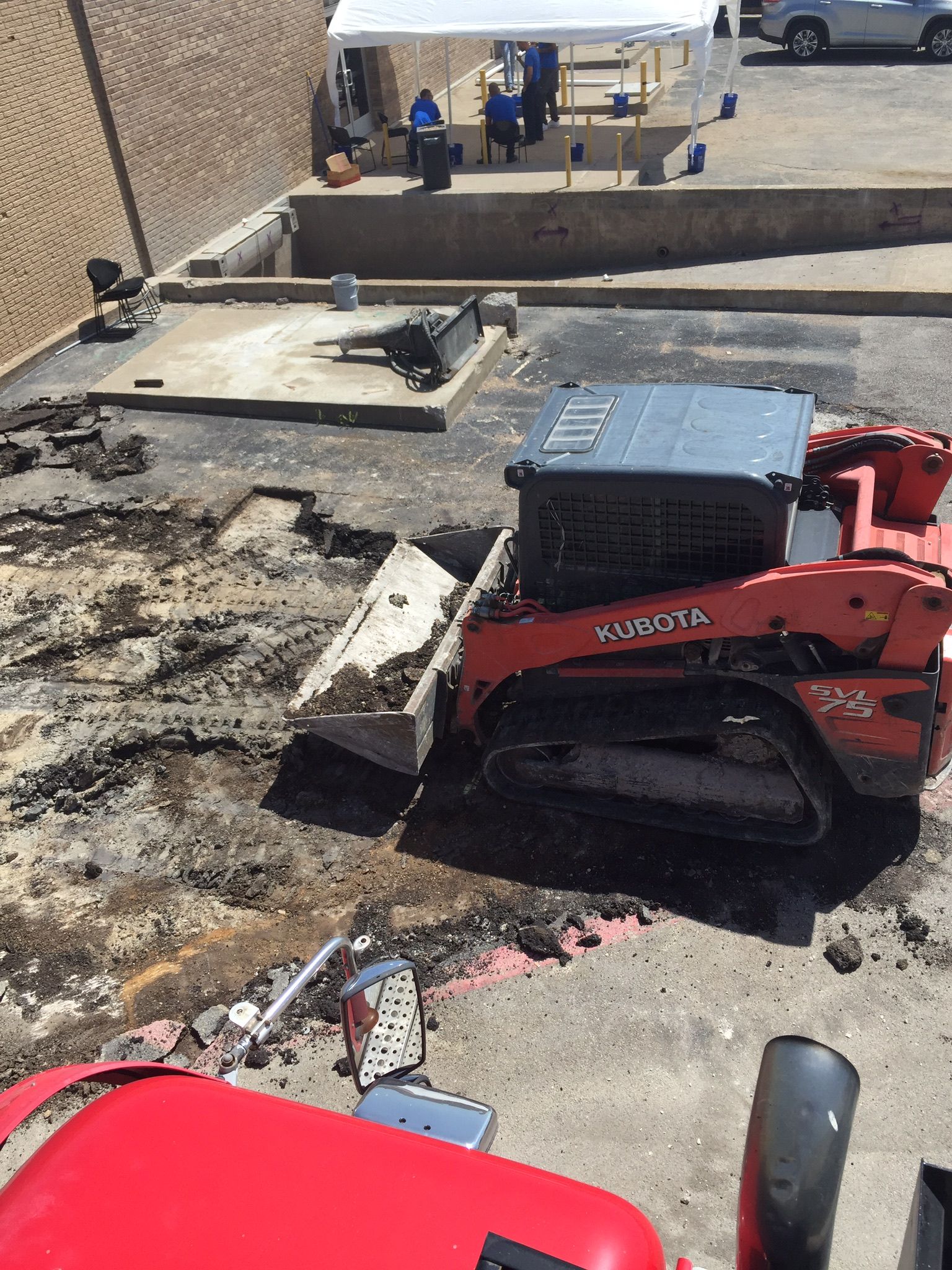 Red Bobcat skid steer working on charred rooftop beside a damaged roof area.