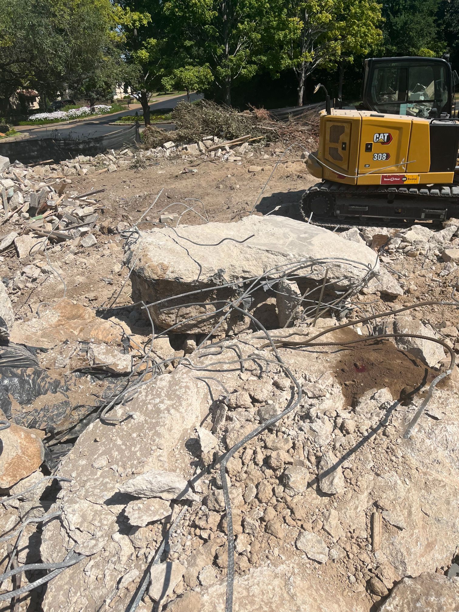 Yellow excavator amid rubble and broken concrete at a demolition site