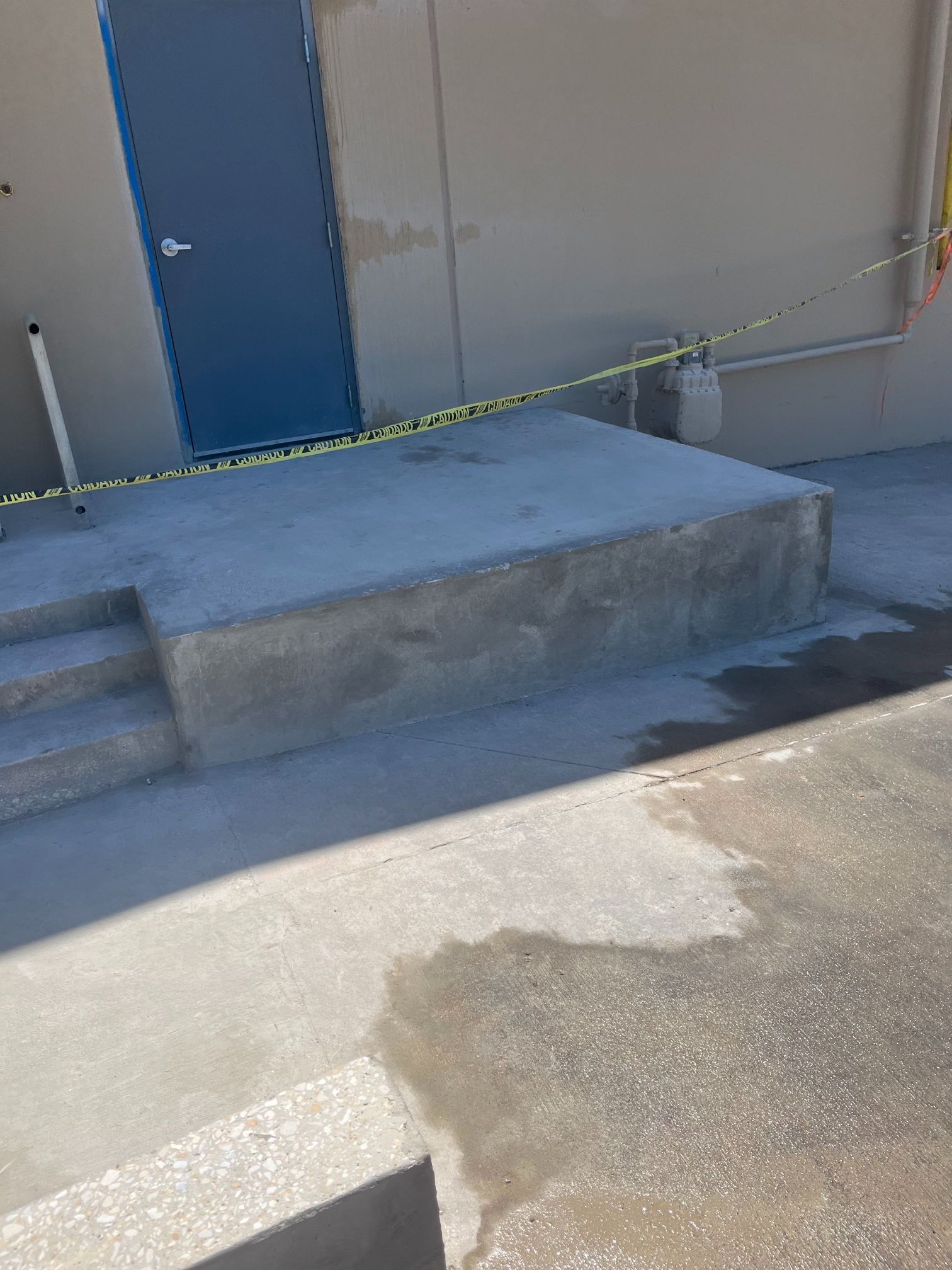 Concrete loading dock with blue door, steps, and yellow caution tape blocking access