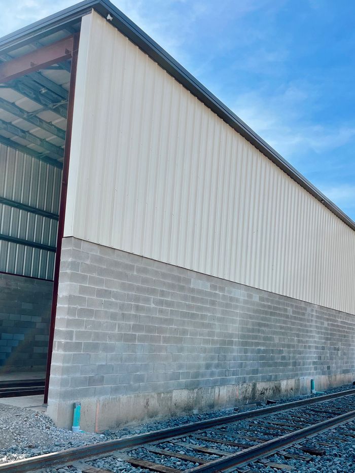 Industrial warehouse exterior with corrugated metal siding and railroad tracks beside it
