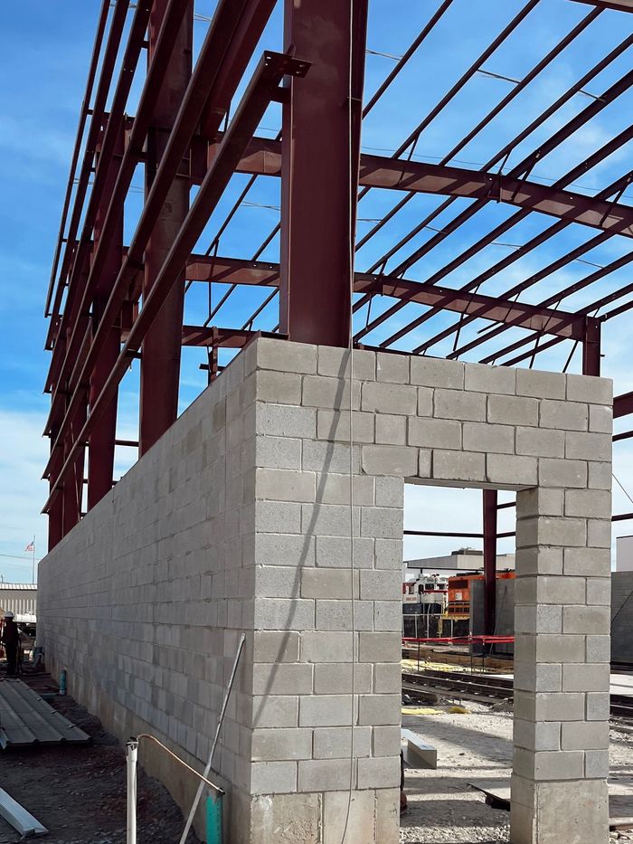 Partially built concrete block structure beside a red steel frame at a construction site
