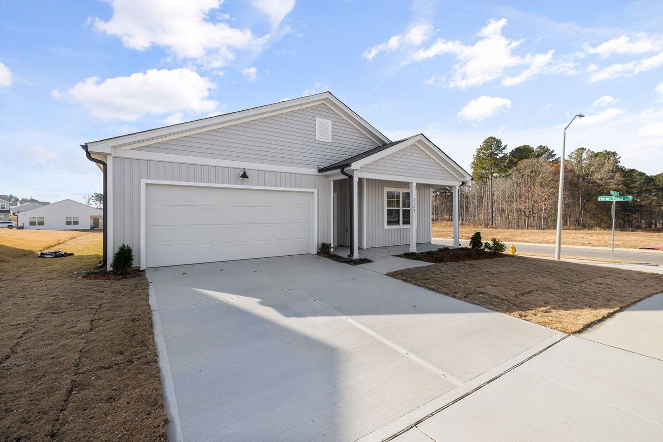 Single-story gray house with a two-car garage and concrete driveway under a clear sky