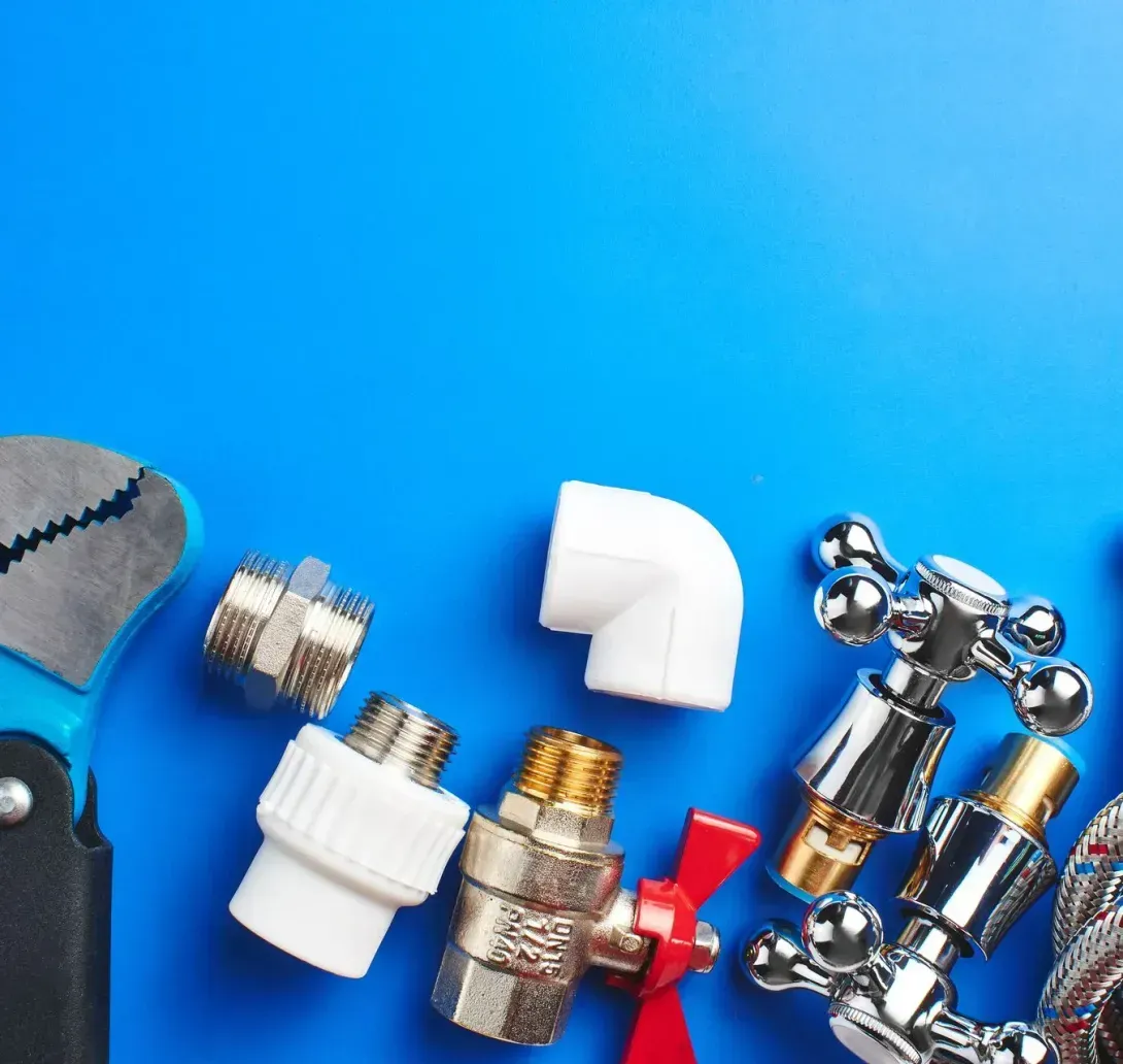 Plumbing tools and hardware, including a wrench, valves, and metal hoses, arranged on a bright blue background.