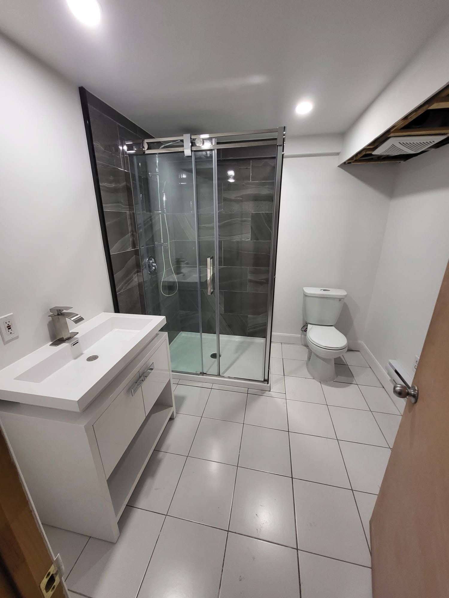 Salle de bains moderne avec douche en verre, meuble-lavabo blanc, toilettes et sol carrelé