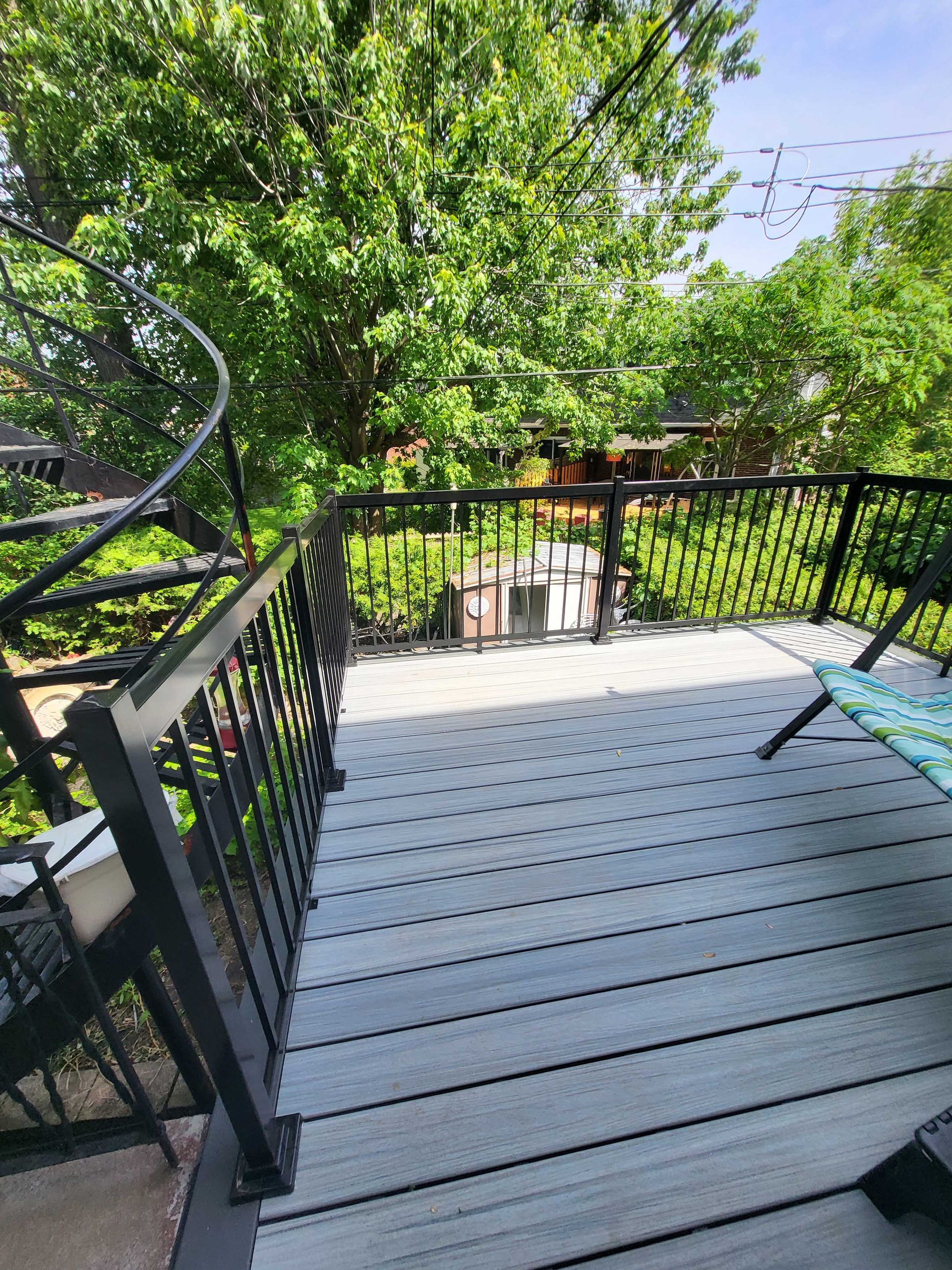 Terrasse noire avec rambarde donnant sur un jardin verdoyant et arboré