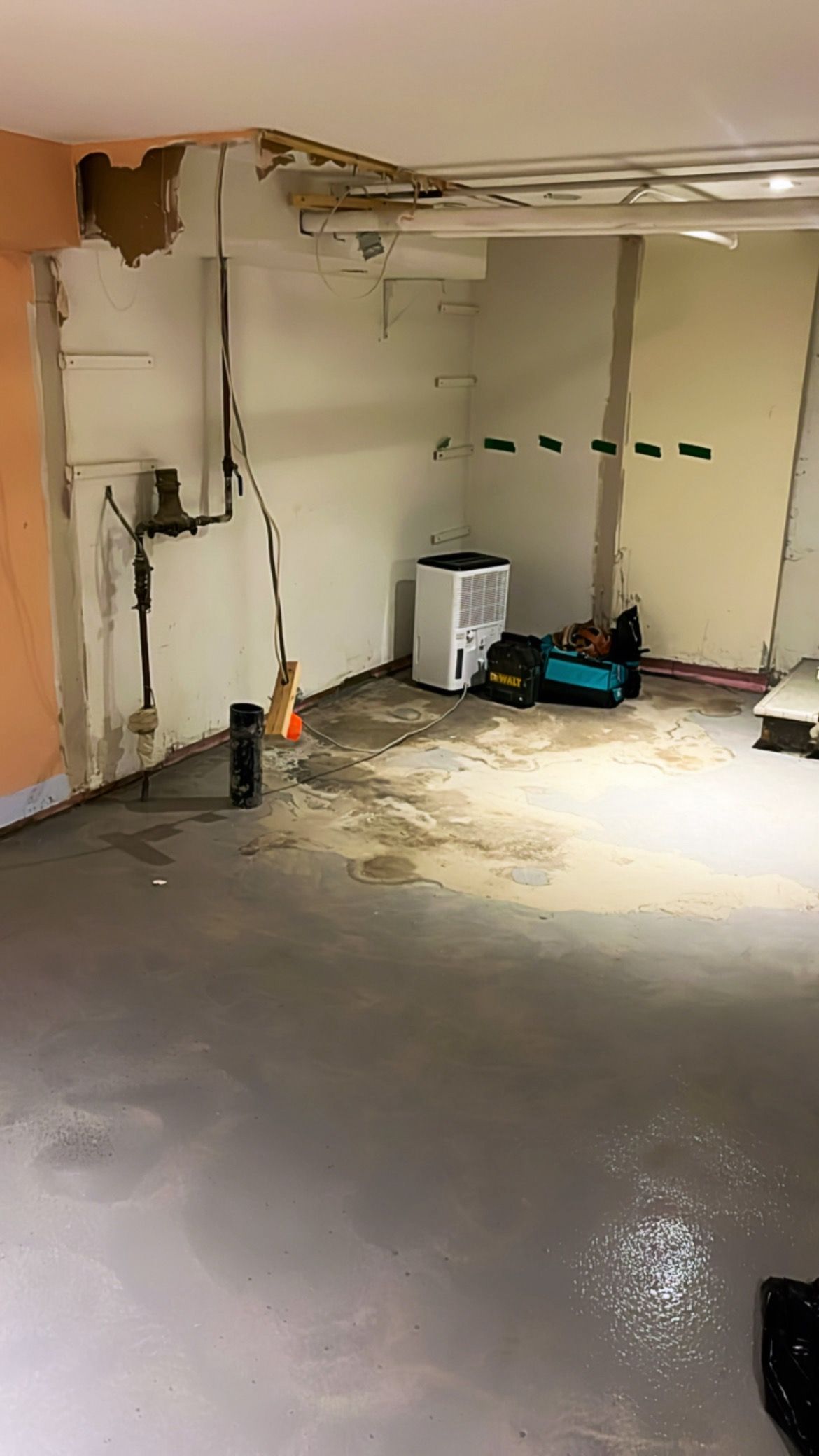 Garage partiellement aménagé avec murs apparents, outils et sol en béton