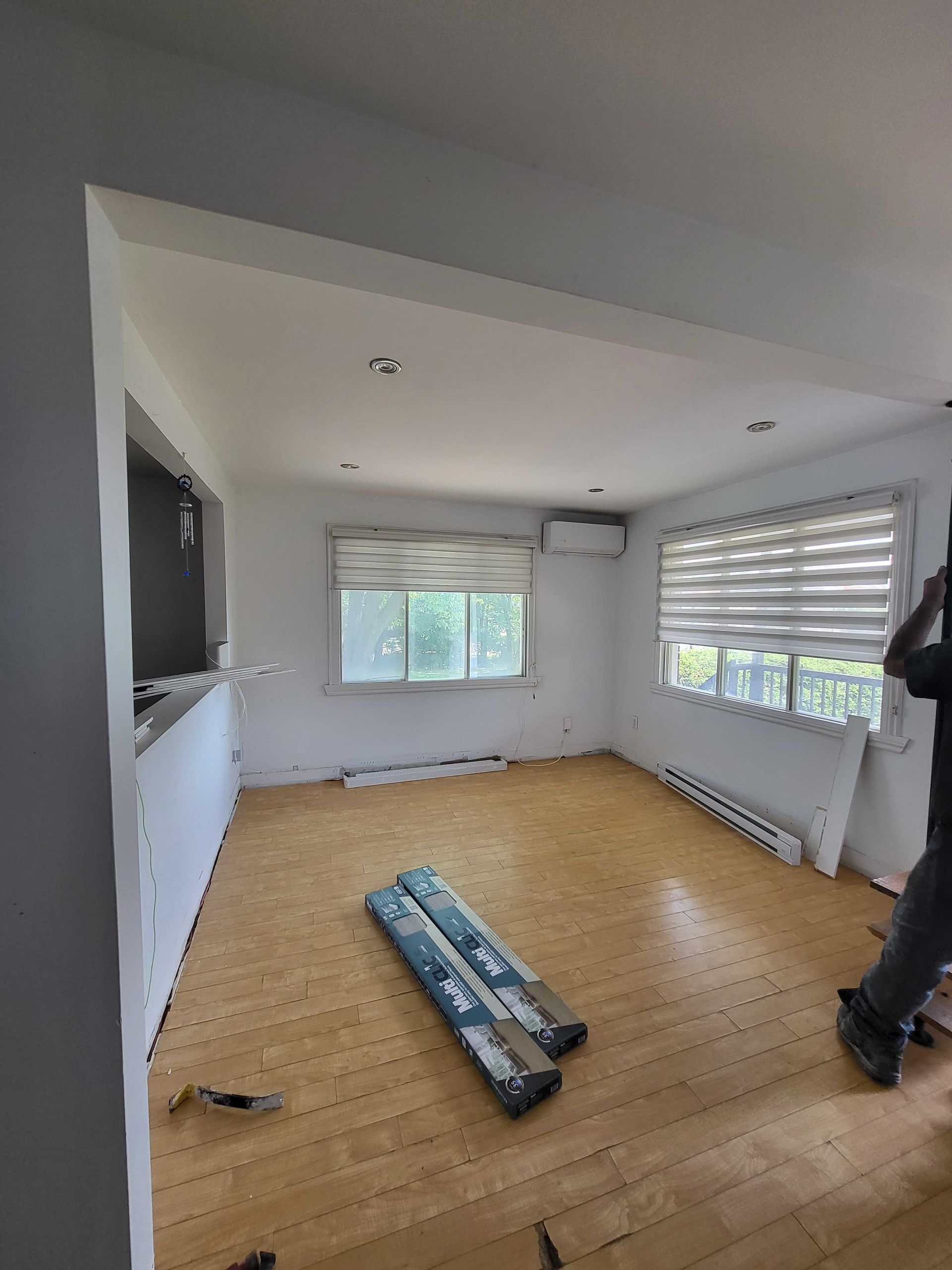 Pièce vide avec parquet brut, fenêtres et matériaux de construction au sol