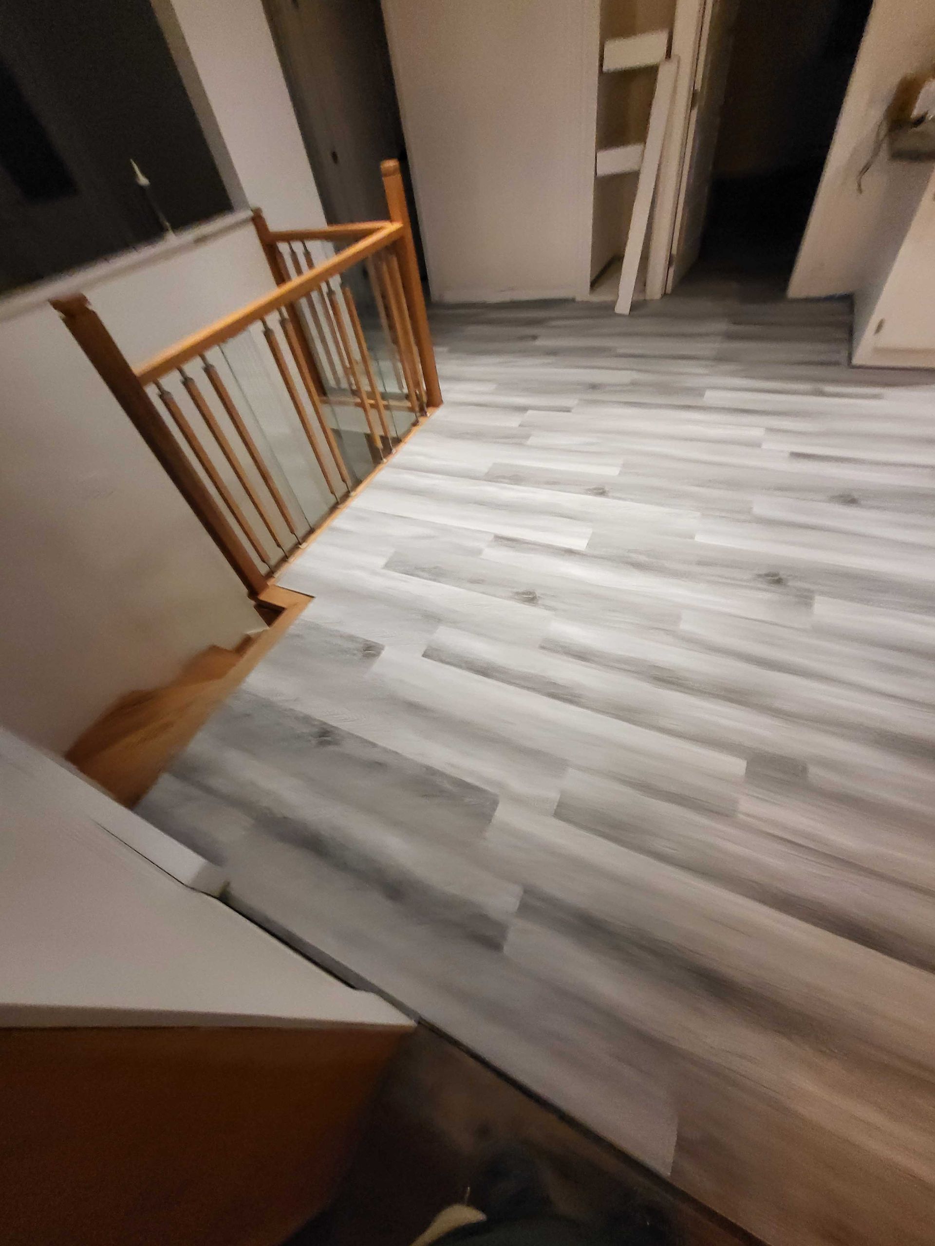 Couloir intérieur avec parquet clair, rampe et portes ouvertes donnant sur les pièces