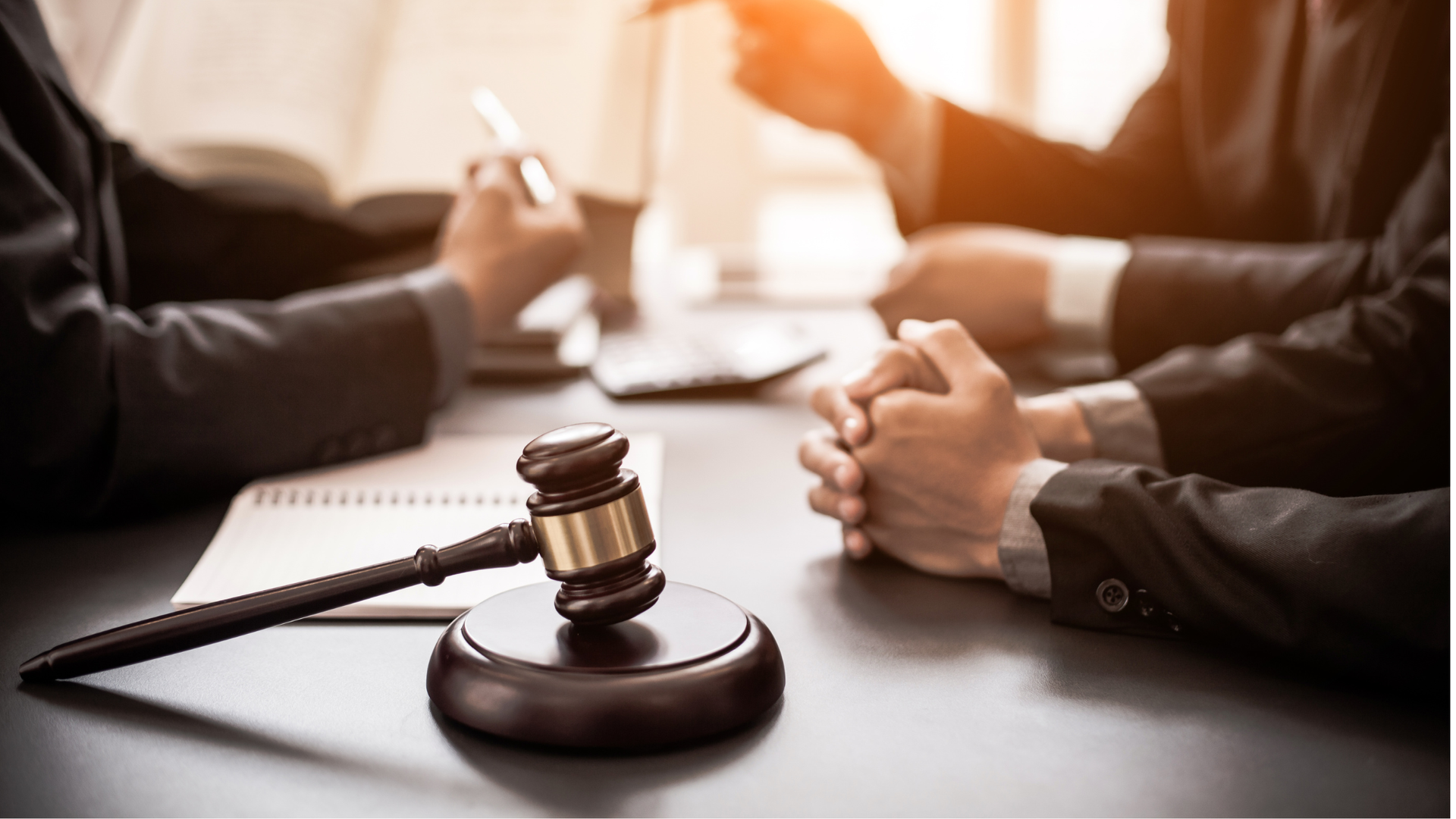 Business professionals meet with legal counsel across a conference table, with a judge's gavel in th