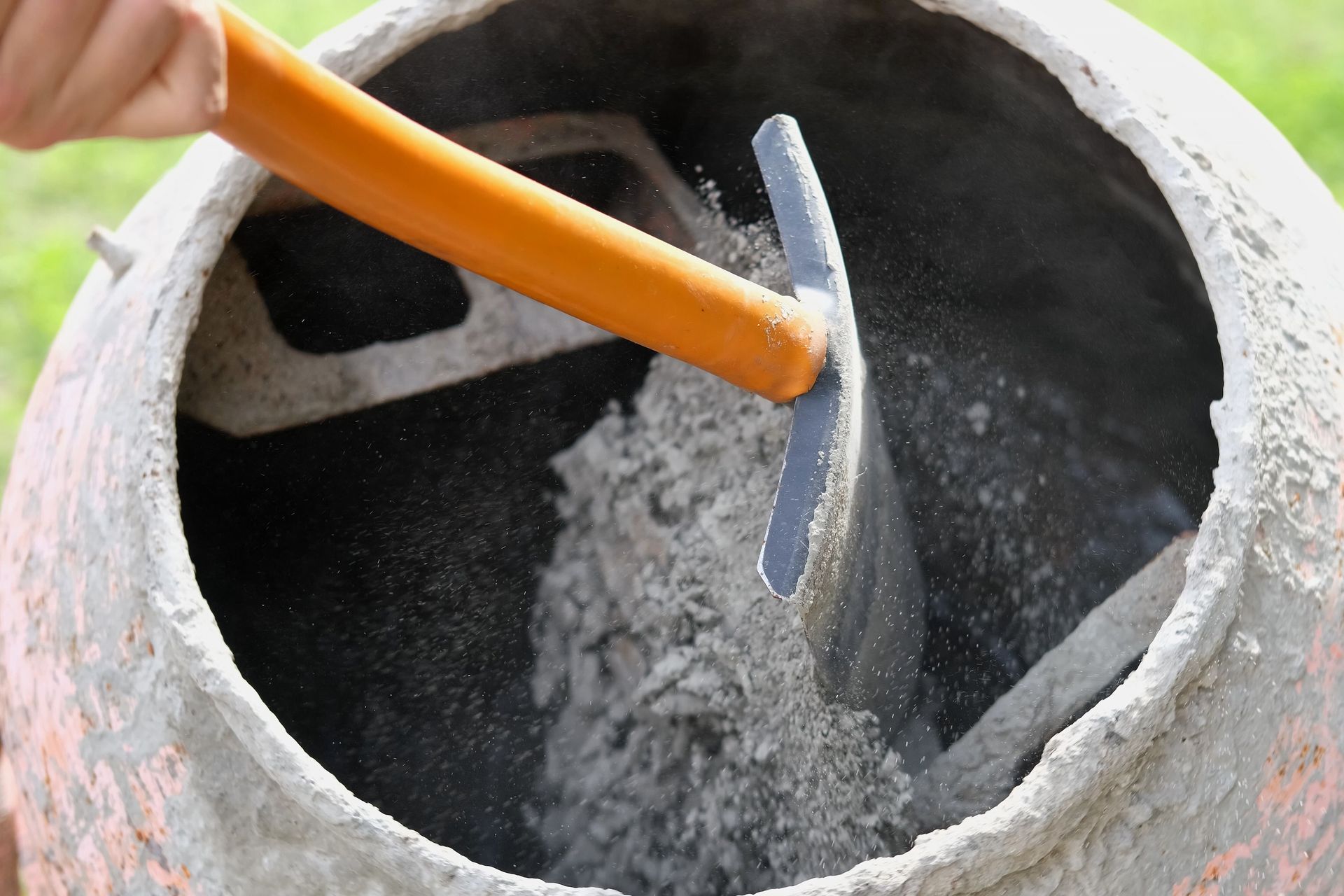 A person is mixing cement in a concrete mixer
