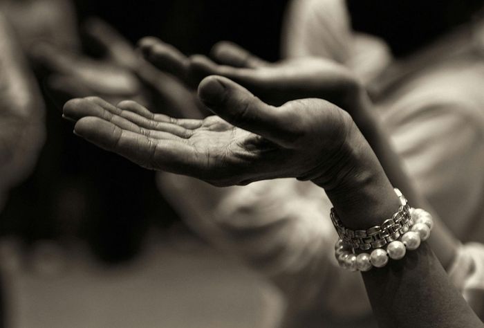 Hands open, palms up, wearing a pearl bracelet, in prayer or supplication.
