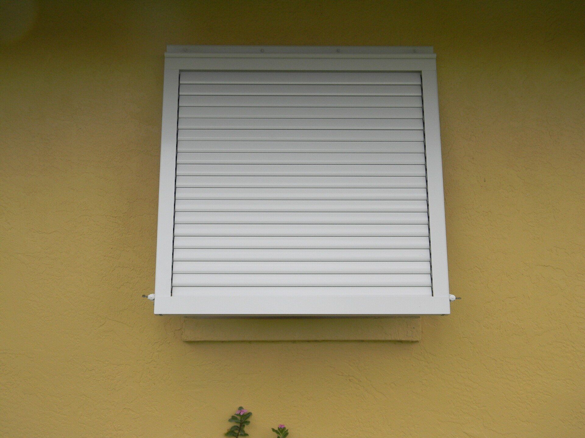 Closed Window Shutter In A Yellow Wall — Reliable Shutter Co., Inc. — Venice, Florida