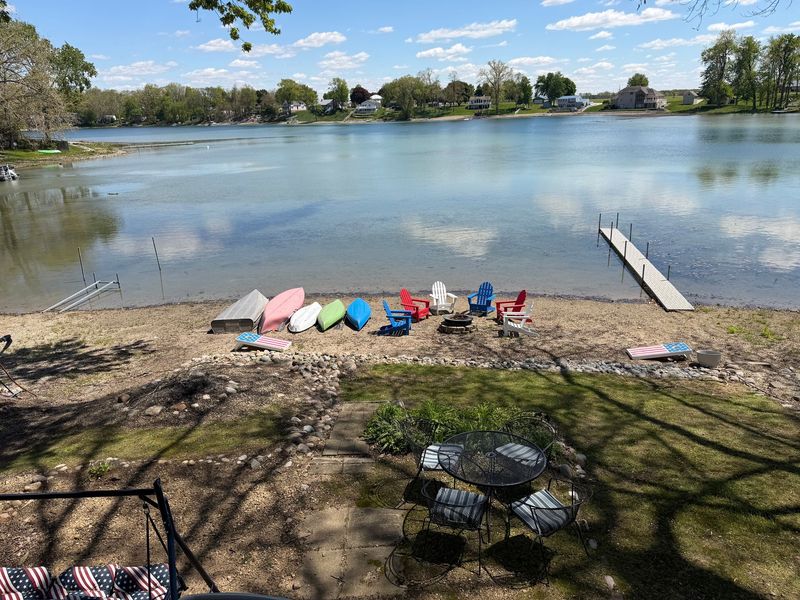 Lakeside home with wooden deck, dock, and kayaks on a cloudy day.