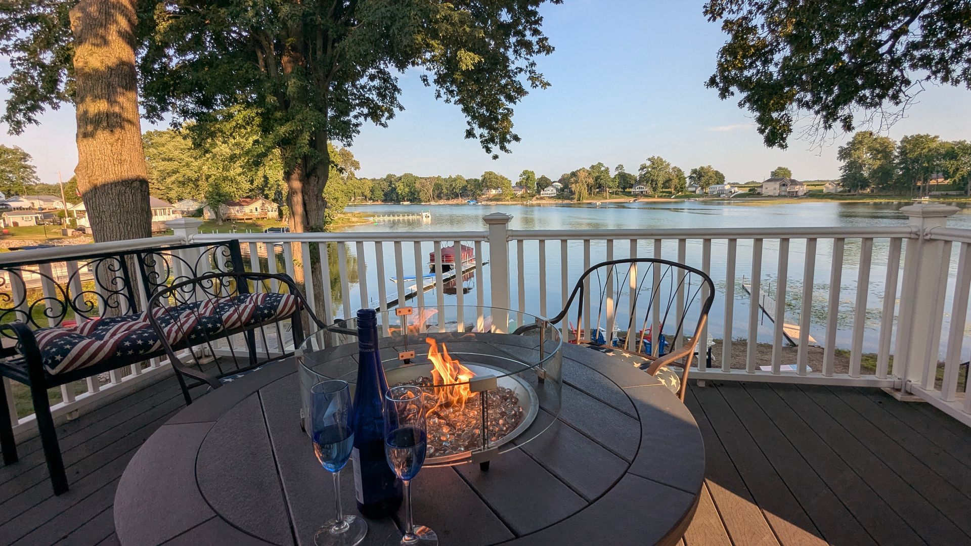 Patio fire pit with chairs overlooking a calm lake at sunset