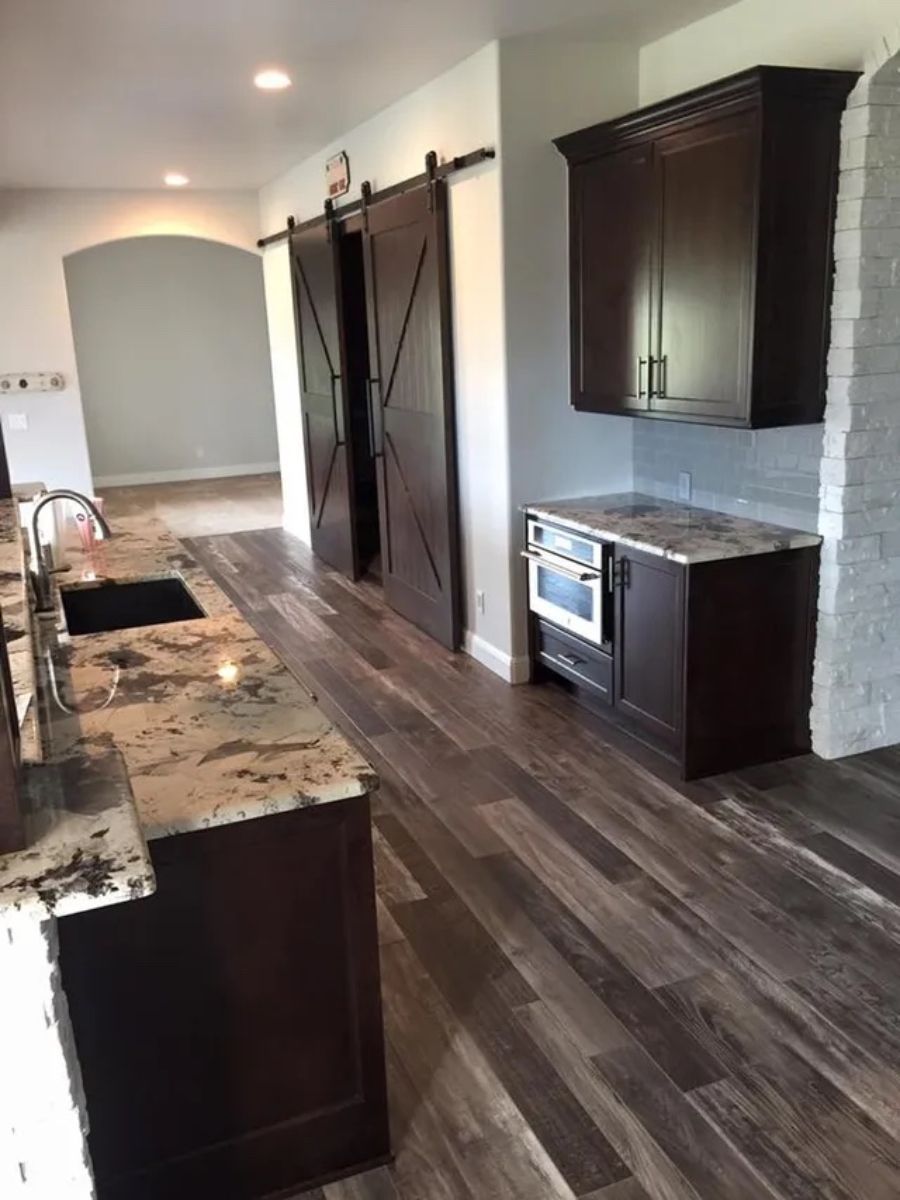 a kitchen with a sink , stove , cabinets and sliding barn doors .