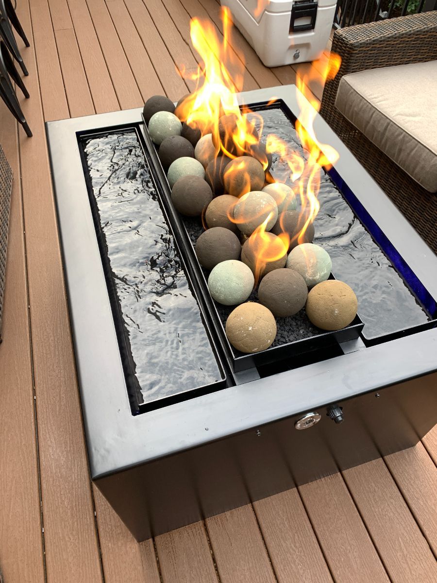 a fire pit filled with rocks is sitting on a wooden deck .