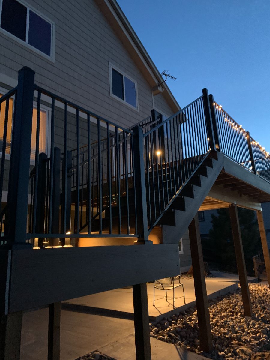 a deck with stairs leading up to it is lit up at night