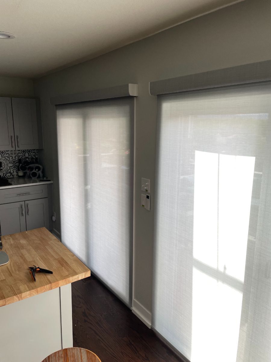 a kitchen with sliding glass doors and blinds on the windows .