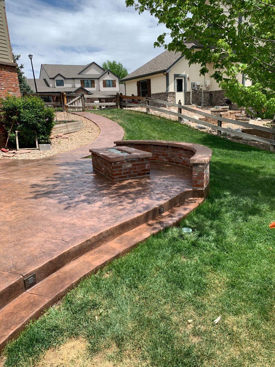 a concrete patio with a fire pit in the backyard of a house .