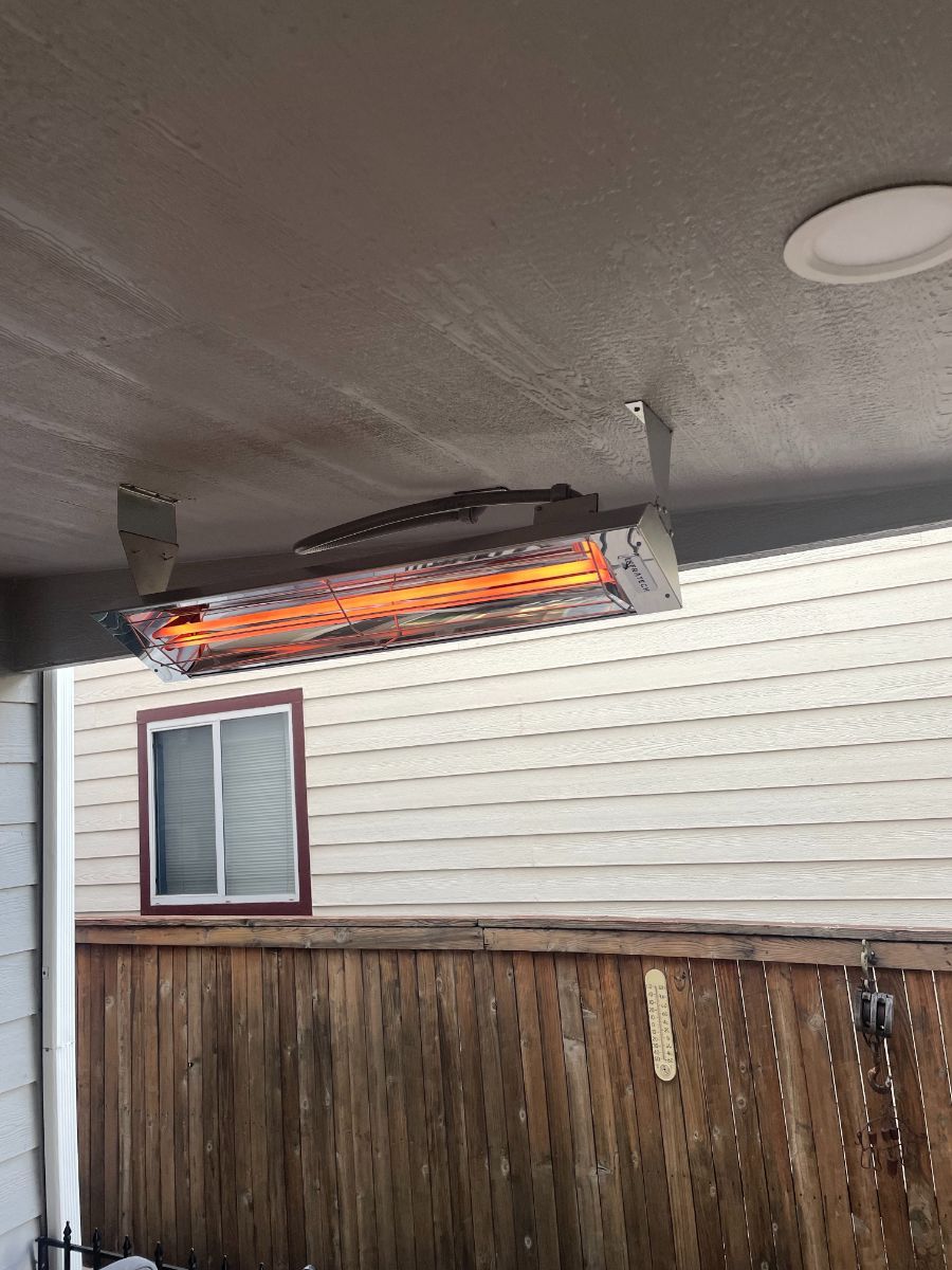 a heater is hanging from the ceiling of a house next to a wooden fence .