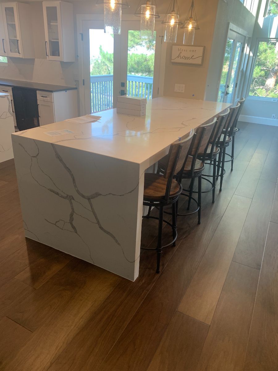 a kitchen with a large island and chairs in it .
