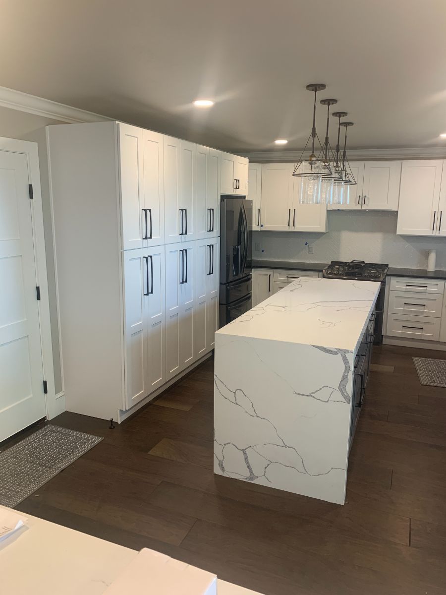 a kitchen with white cabinets and a large island in the middle .