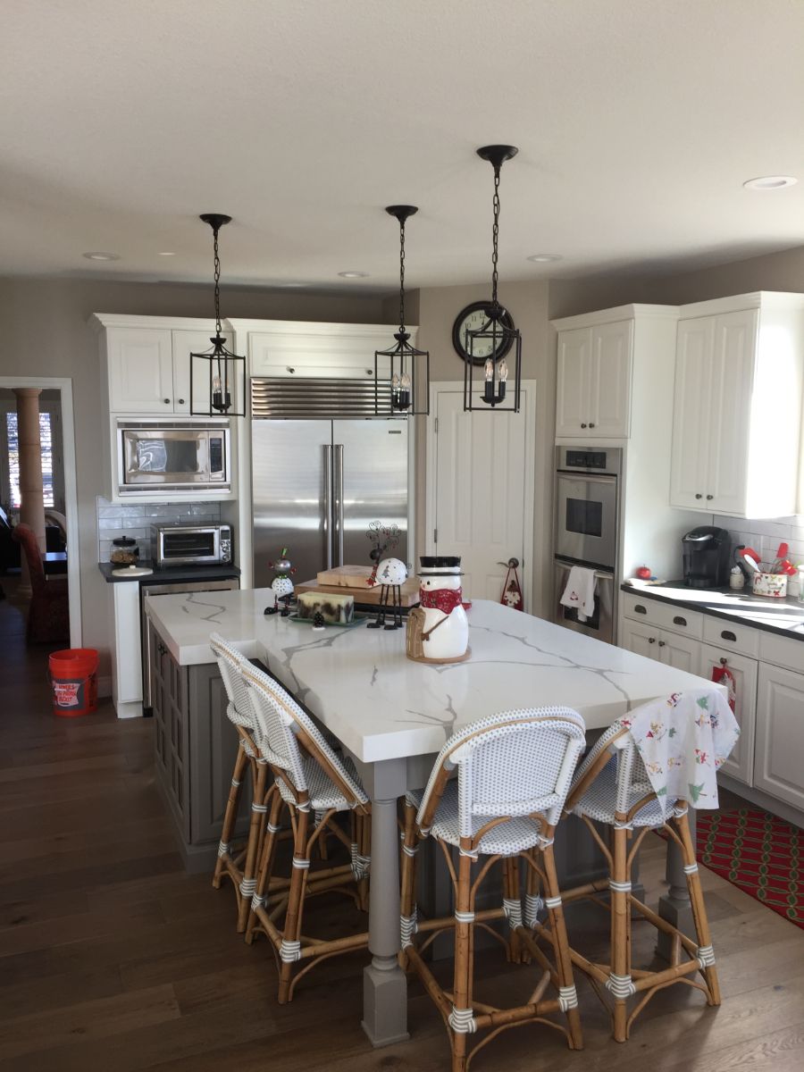 a kitchen with a large island and wicker chairs .