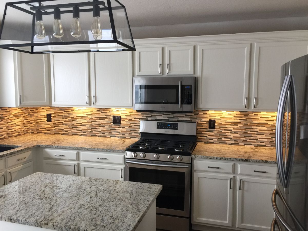 a kitchen with white cabinets , stainless steel appliances and granite counter tops .