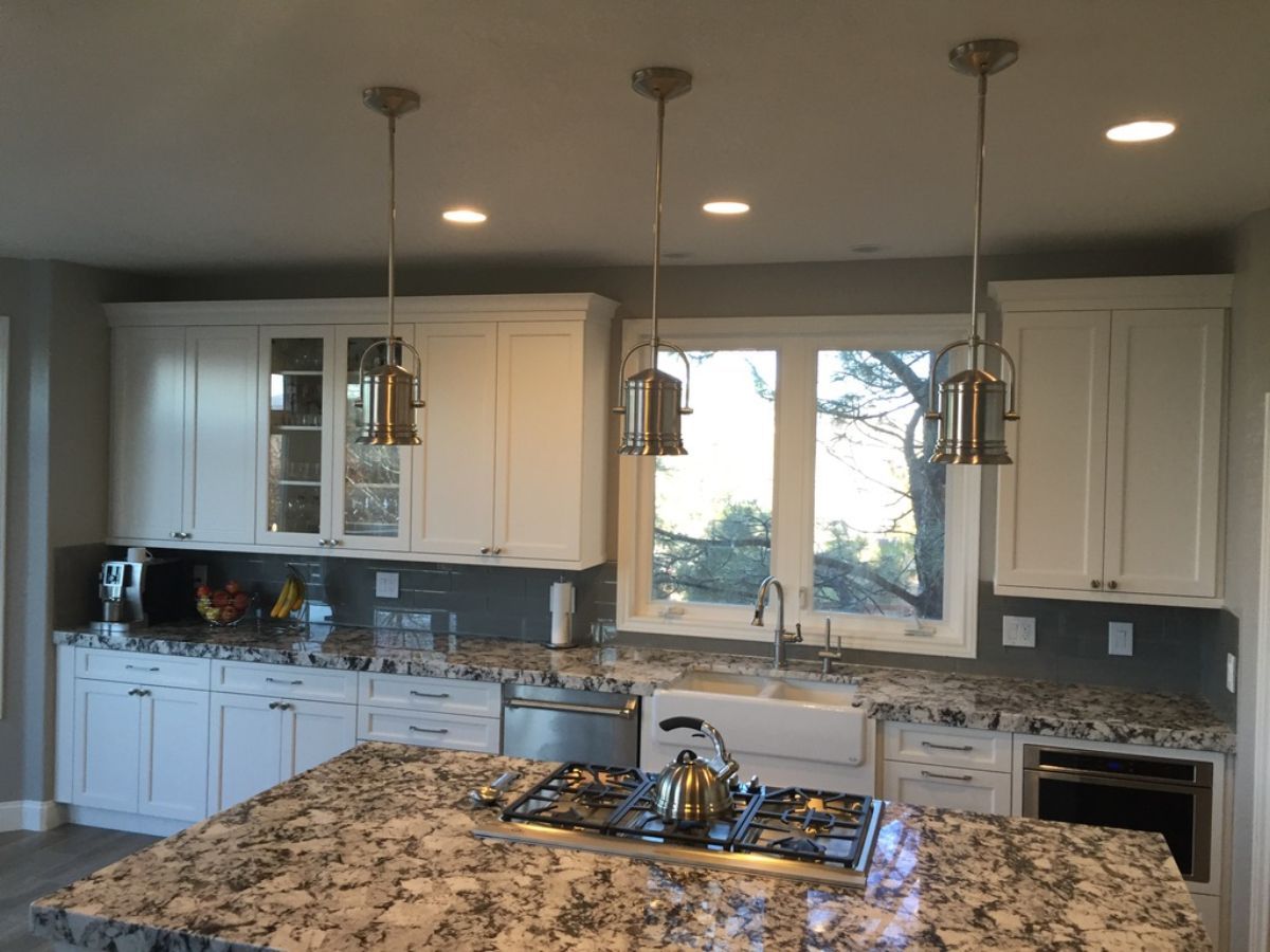a kitchen with white cabinets and granite counter tops .