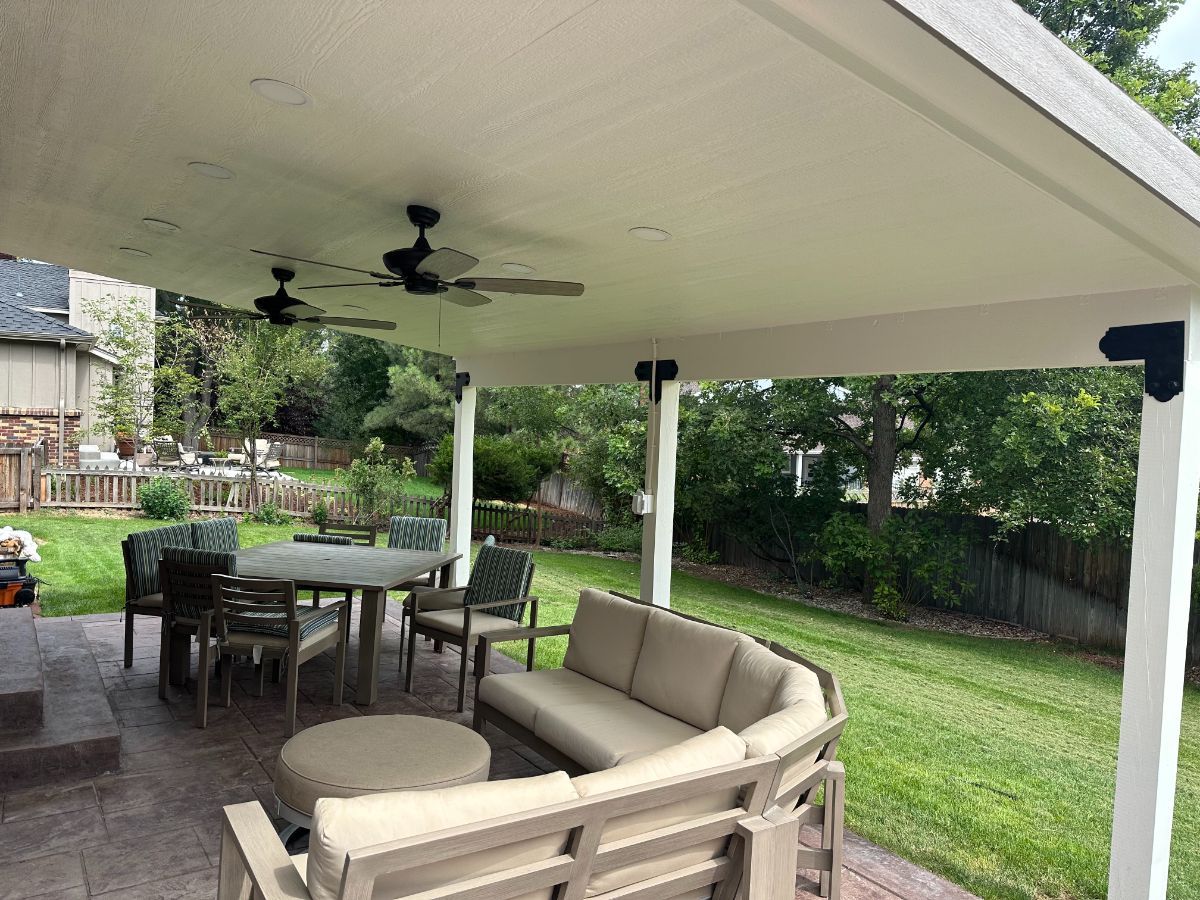 a patio with a couch , table , chairs and a ceiling fan .