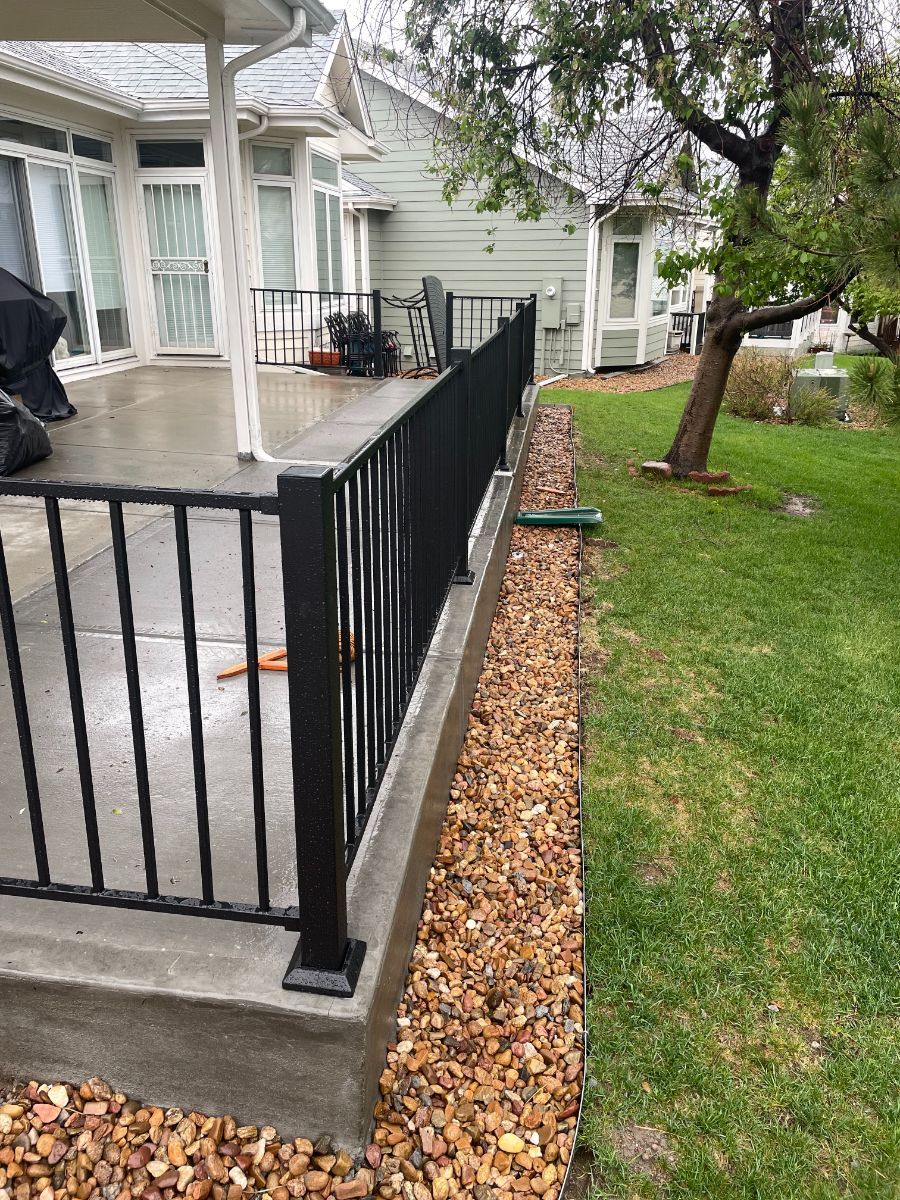 a black wrought iron fence surrounds a patio in front of a house .