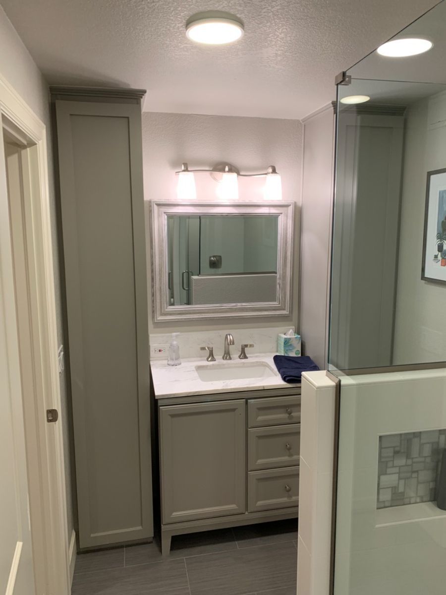 a bathroom with a sink , mirror and cabinets