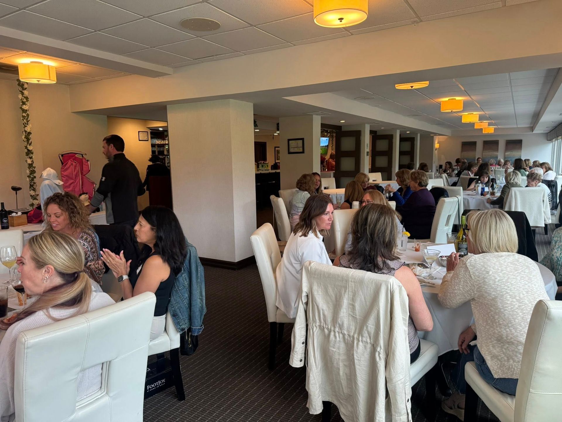 People seated at tables in a brightly lit restaurant, likely attending a luncheon.