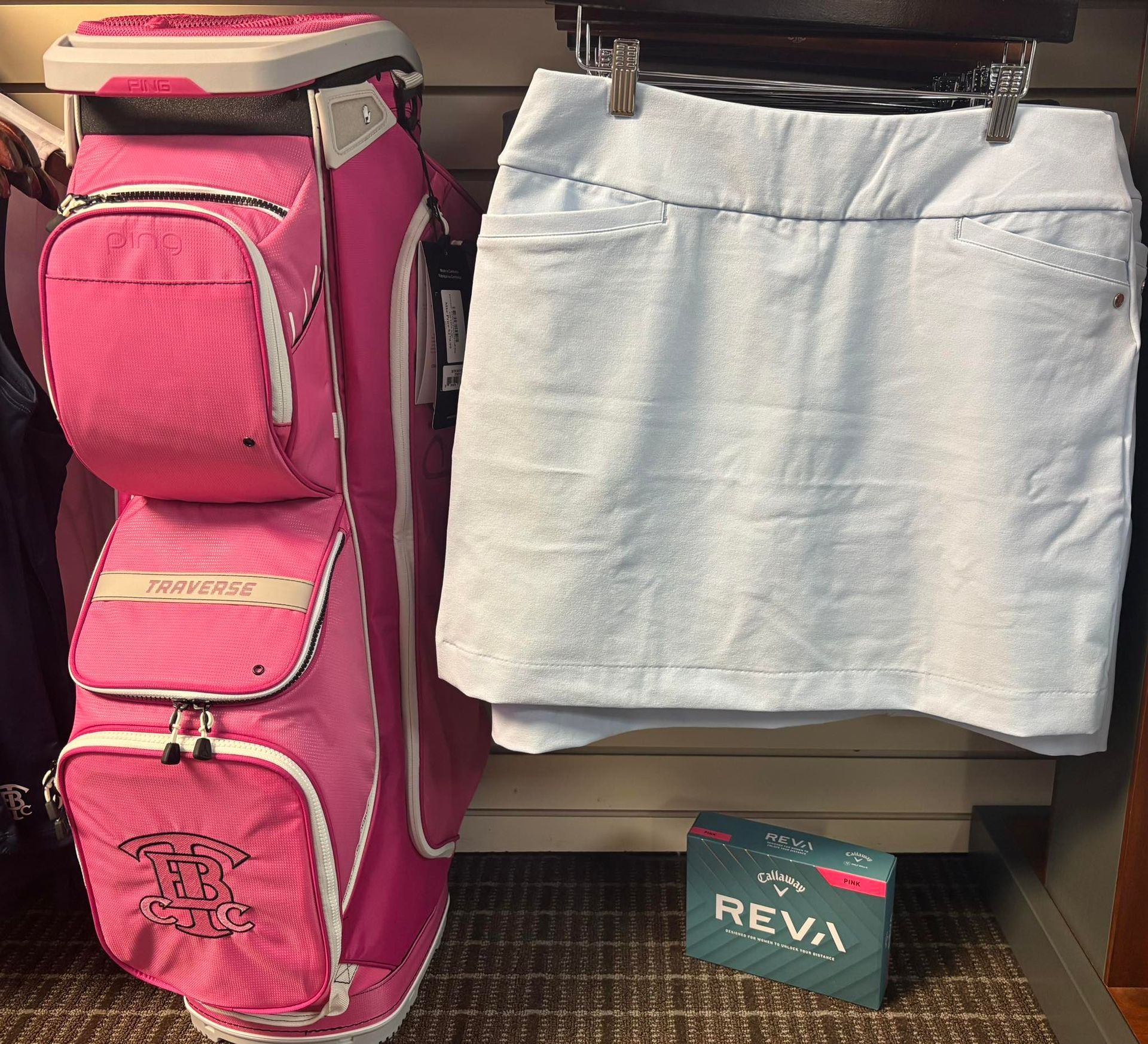 Pink golf bag and light blue skort displayed for sale.