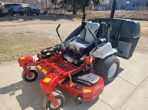 Red and silver riding lawn mower with a grass catcher on a concrete surface.