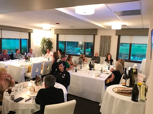 People seated at tables in a brightly lit dining room for an event.